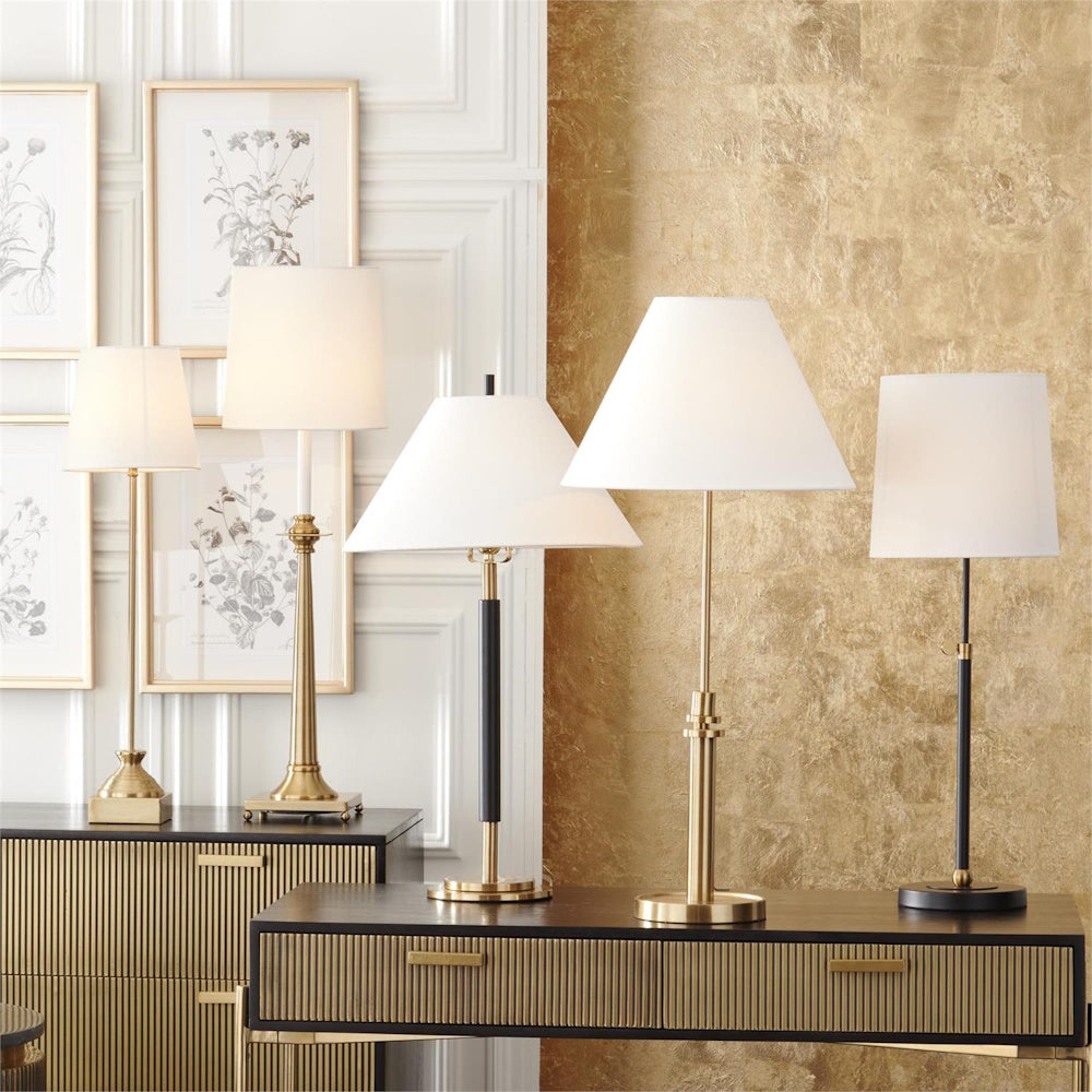 Modern brass and black table lamps with white shades displayed on a fluted wood console table.
