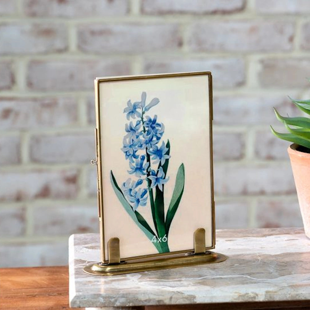 Antique brass 4x6 vertical photo frame with a blue hyacinth botanical print on a marble surface with brick background.