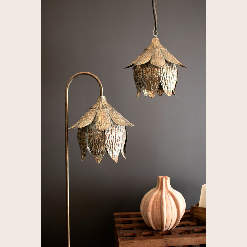 Antique brass tulip floor lamp and matching pendant light with a textured floral design against a dark wall.
