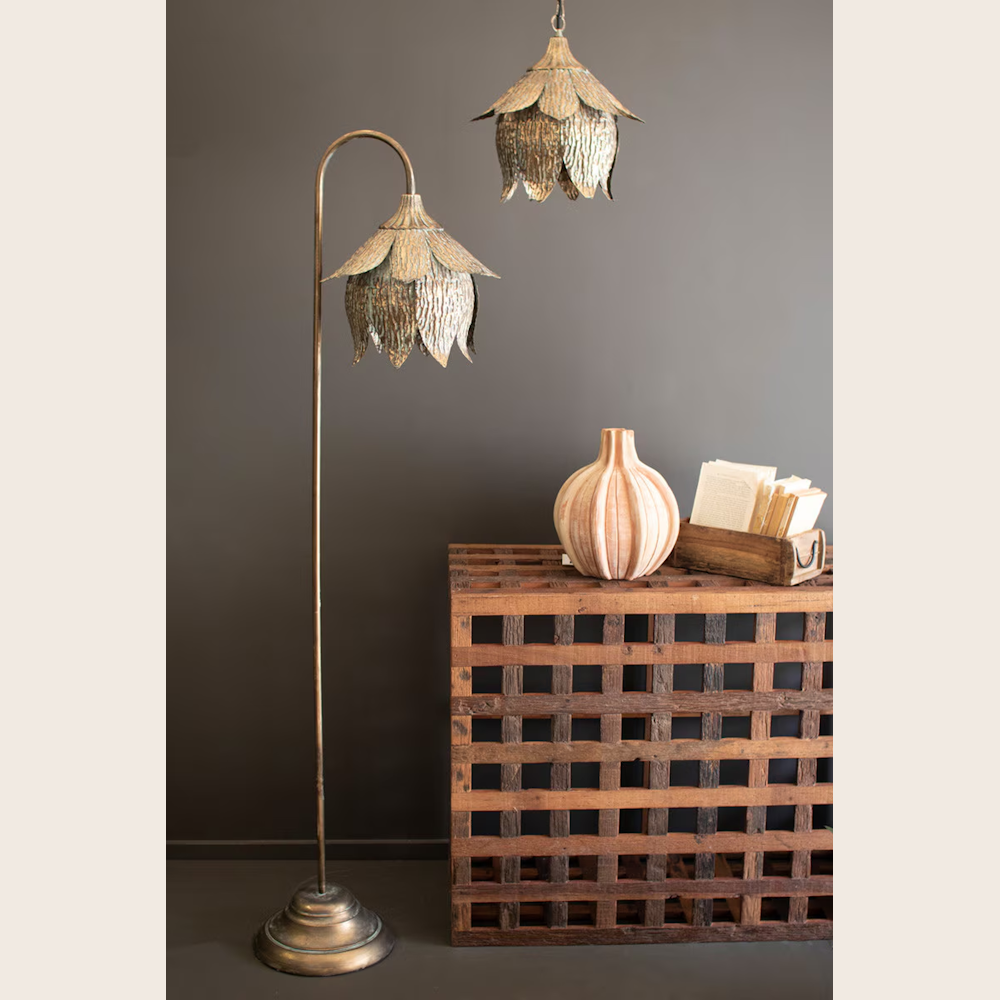 Antique brass tulip floor lamp and matching pendant light next to a rustic wooden crate and decorative vase.