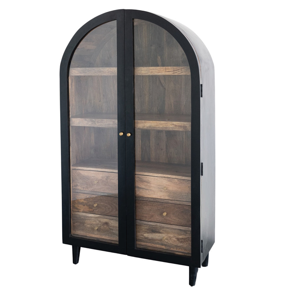 Arched black mango wood cabinet with two glass doors, internal shelves, and drawers with gold hardware on a white background.