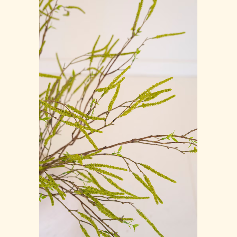 Artificial green willow flower spray with long textured catkins and small budding leaves on brown branches.