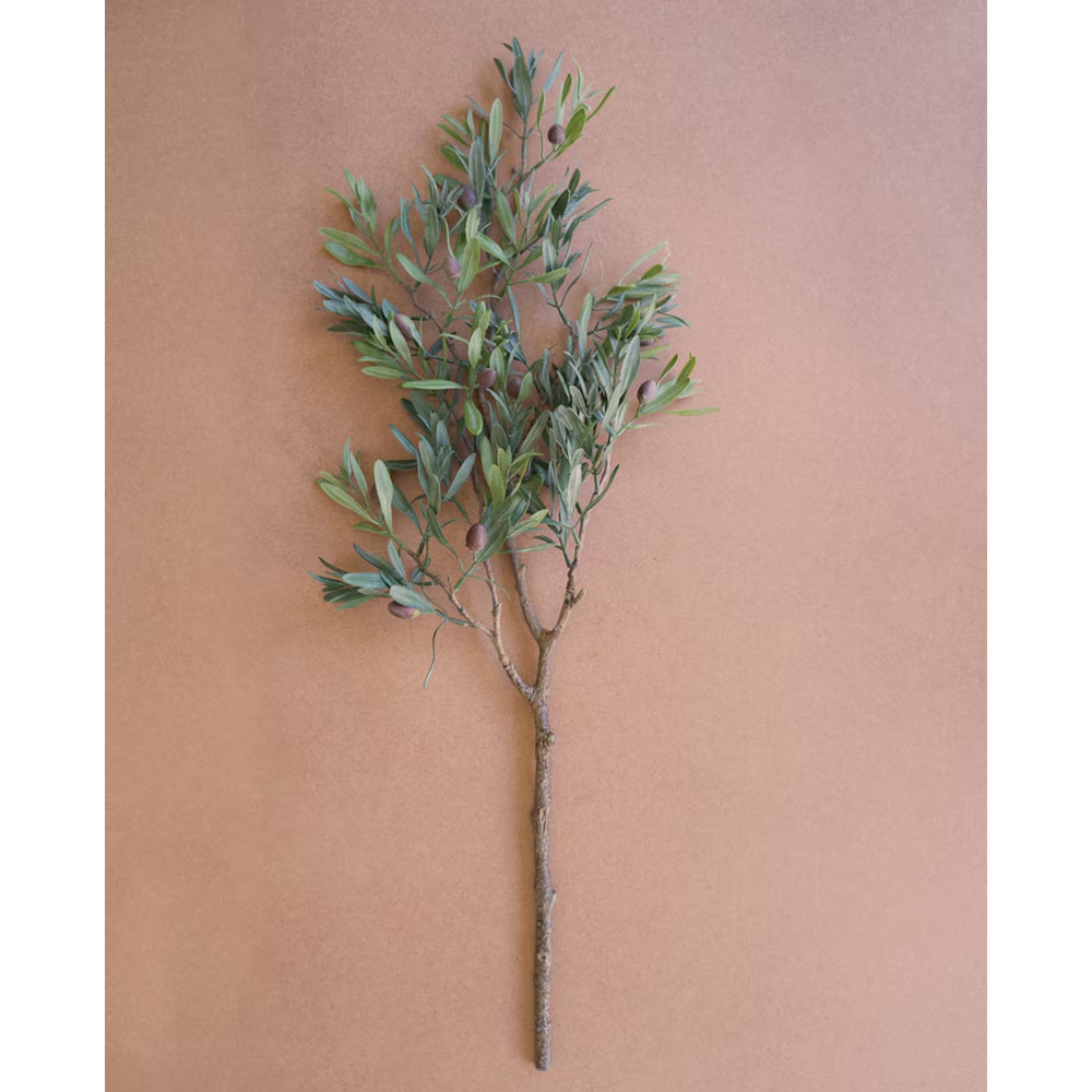 Realistic artificial olive branch with green leaves and dark olives on a warm brown surface.