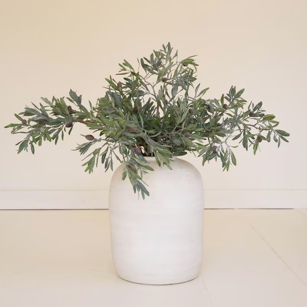 Lush artificial olive branches with dark olives displayed in a large white ceramic vessel.