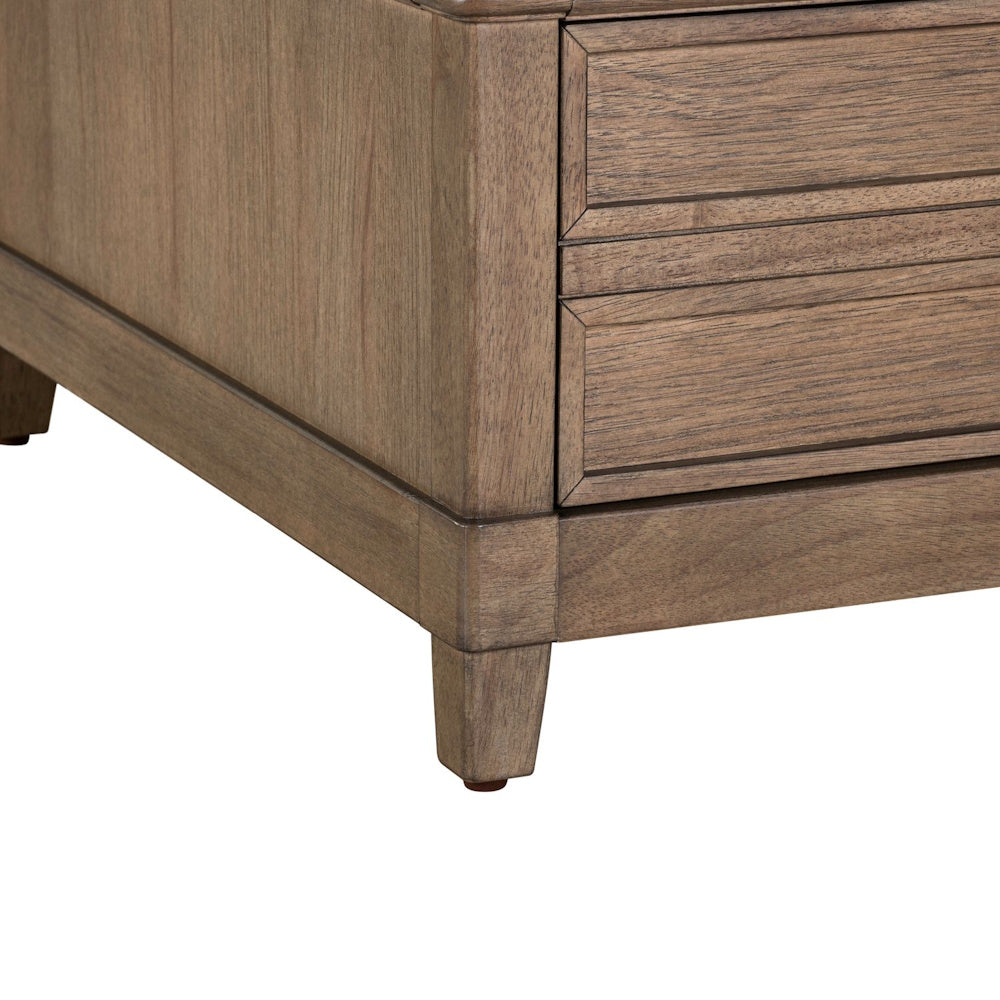 Close-up of the lower corner, tapered leg, and paneled base of a light-brown wooden end table.