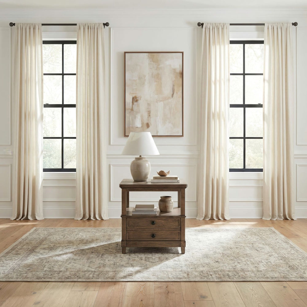 Brown wooden end table with two drawers styled in a bright, modern living room setup.