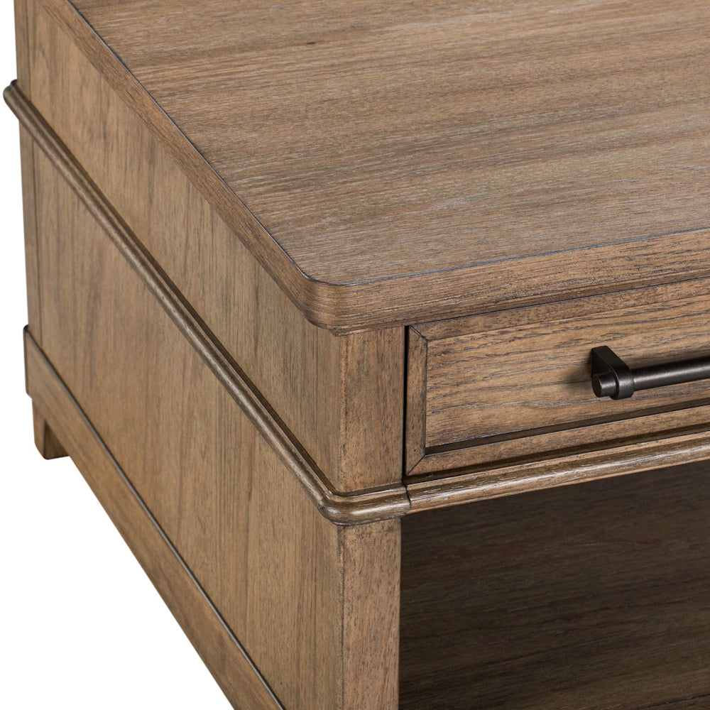 Close-up corner view of a wooden cocktail table with a natural grain finish, drawer, and dark metal pull handle.