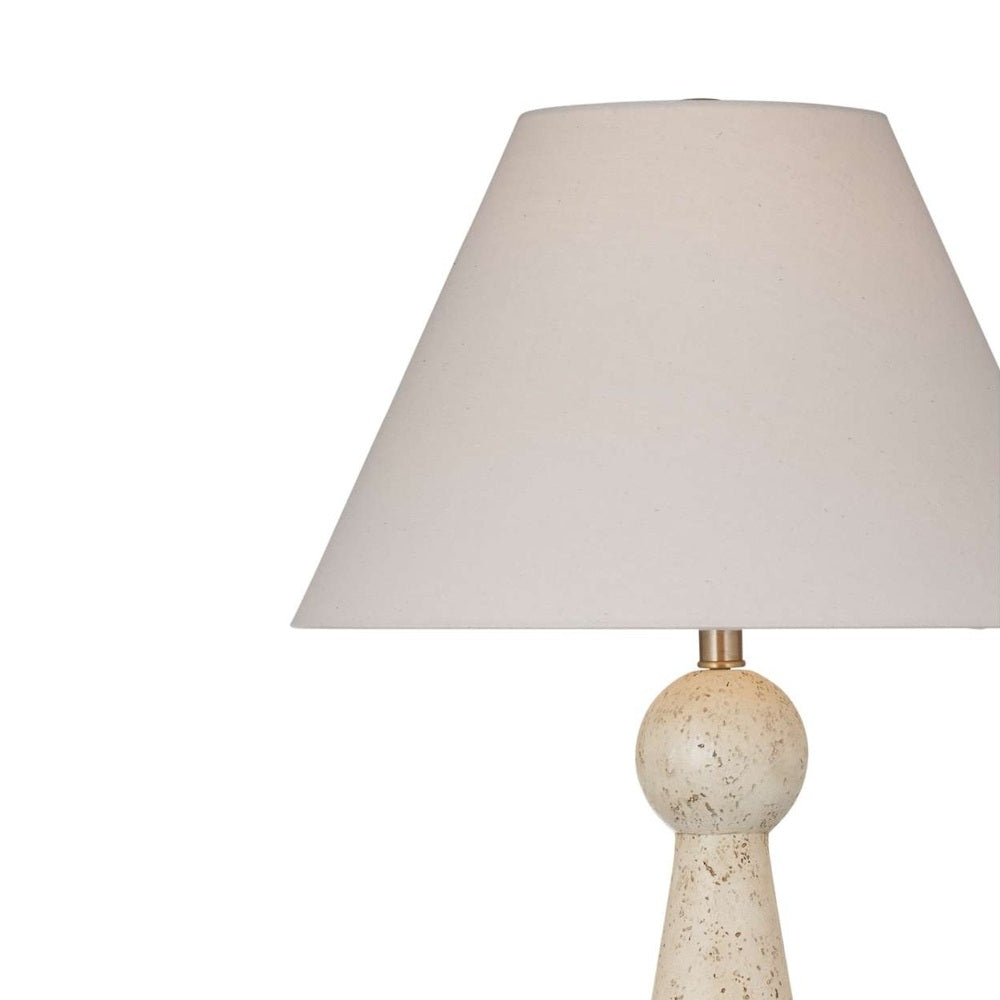 Close-up of a off-white tapered fabric lampshade attached to a speckled beige geometric lamp base.