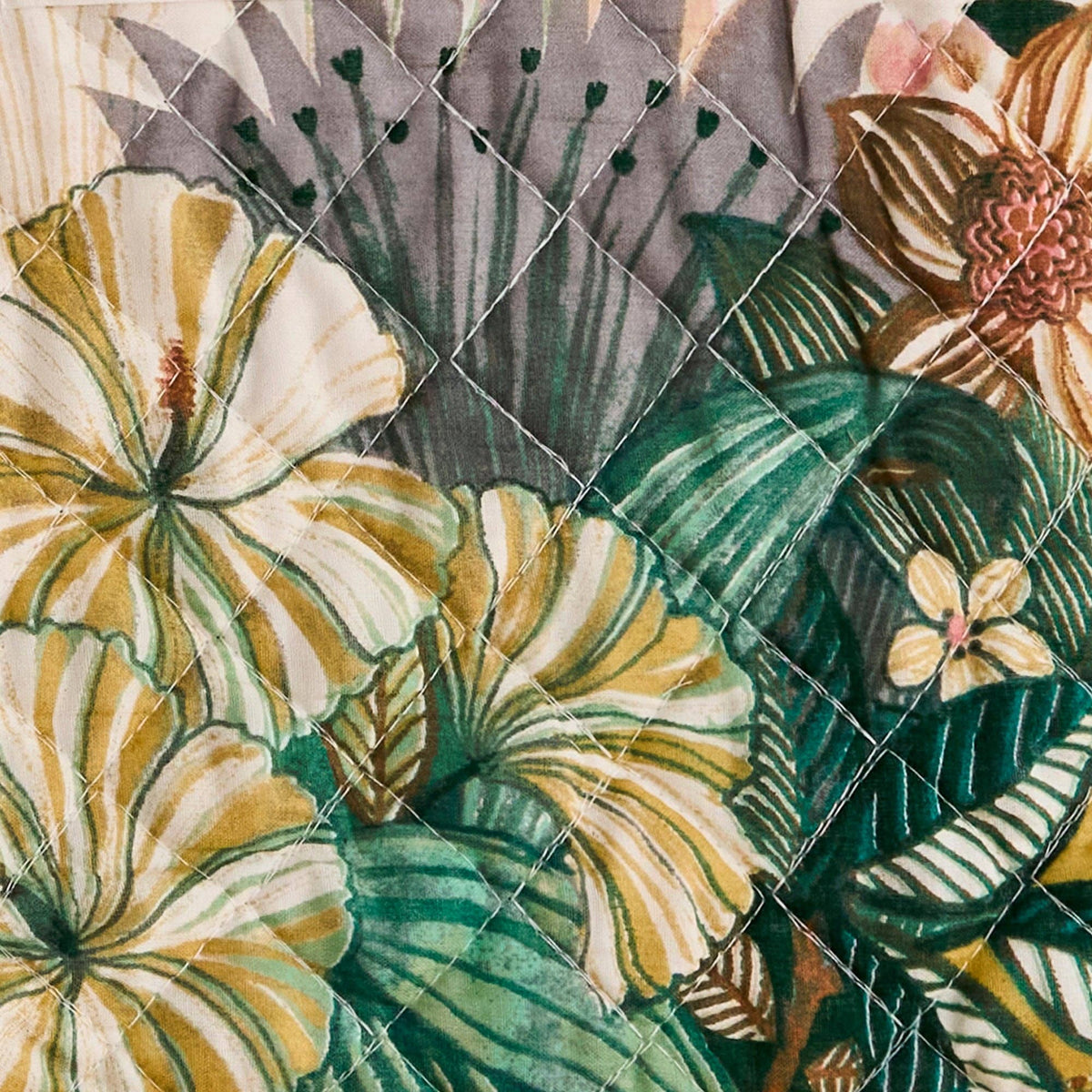 Quilted fabric with a tropical floral pattern featuring green leaves and yellow hibiscus flowers.