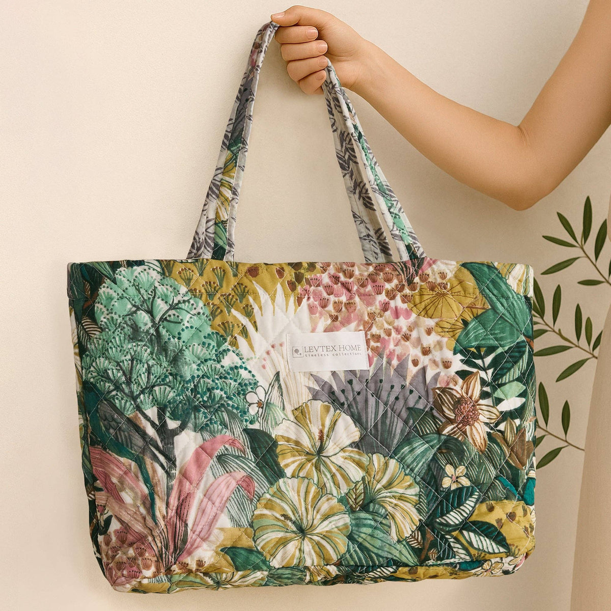 Quilted tote bag with a tropical botanical print in green, pink, and gold by Levtex Home.
