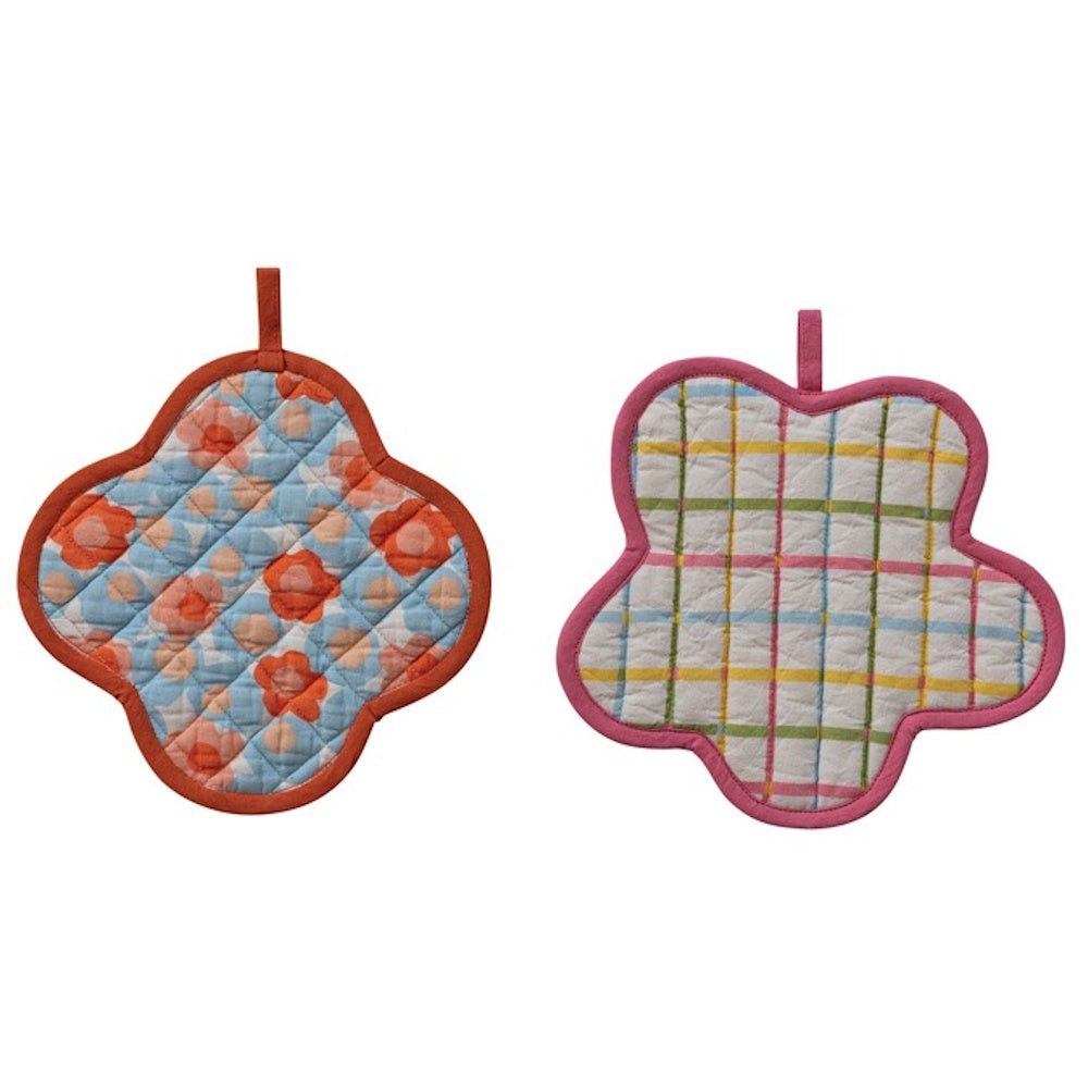 Two quilted, flower-shaped pot holders: one with an orange floral print and one with a colorful plaid pattern.