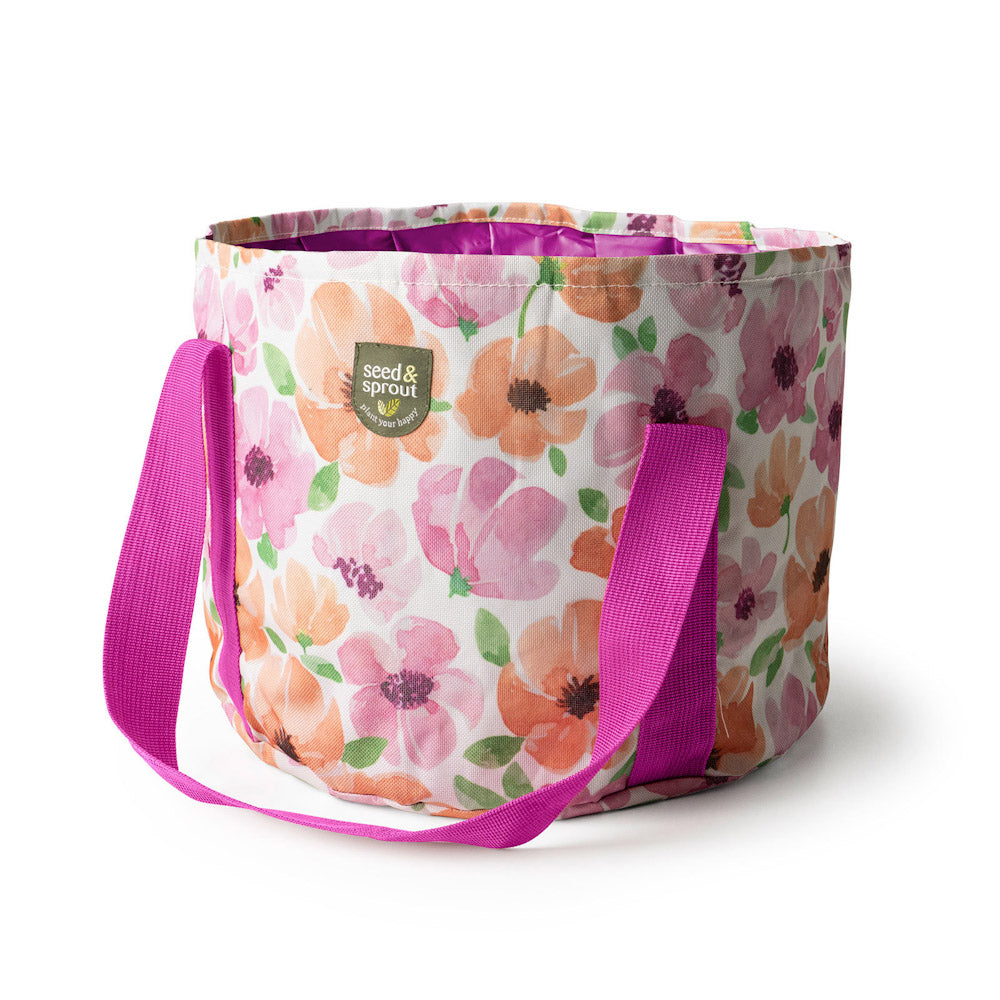 A Seed & Sprout floral fabric storage bin with pink and orange flowers and a pink carrying strap.