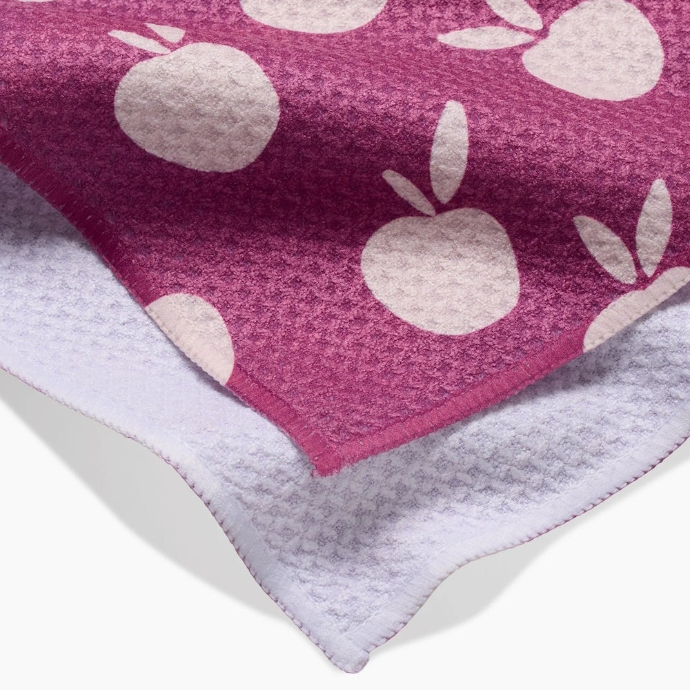 Close-up of a magenta kitchen towel with white apple patterns, folded to show its textured white underside.