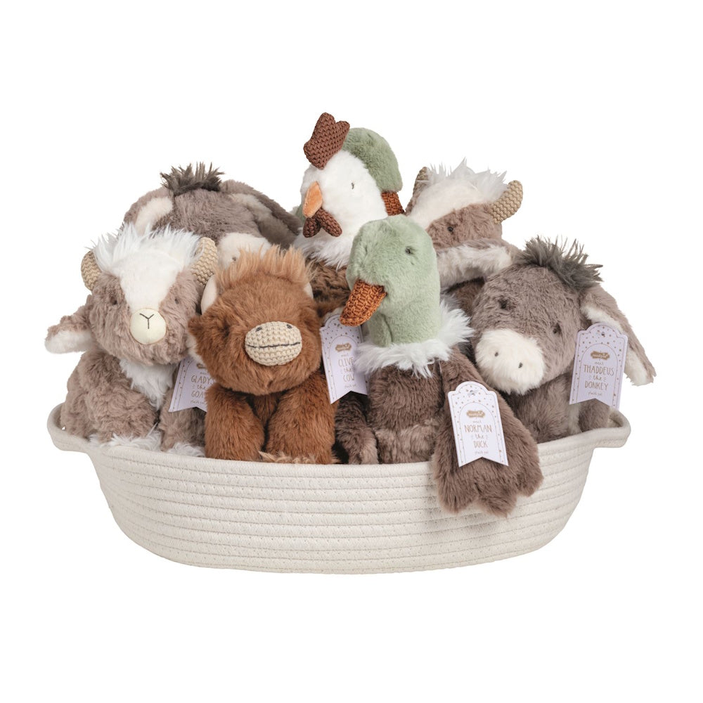 Assorted plush barnyard animal toys with tags sitting inside a white woven storage basket against a plain background.