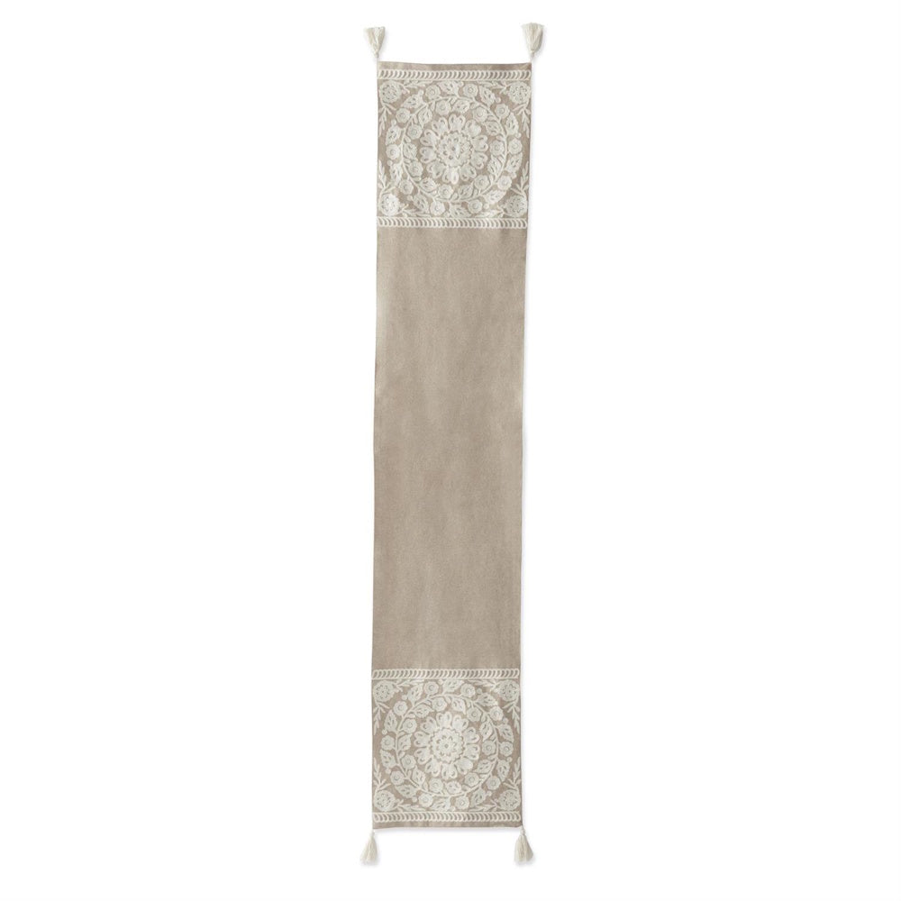 Beige table runner with cream circular floral embroidery, intricate medallions, and corner tassels on a neutral base.
