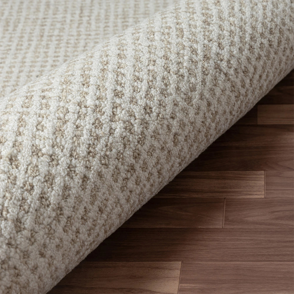 Textured cream wool area rug with a diamond pattern on dark wood flooring.