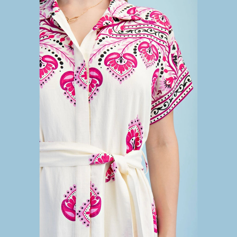 Close-up of a berry-pink printed maxi shirt dress with short sleeves, a floral pattern, and a matching waist tie.