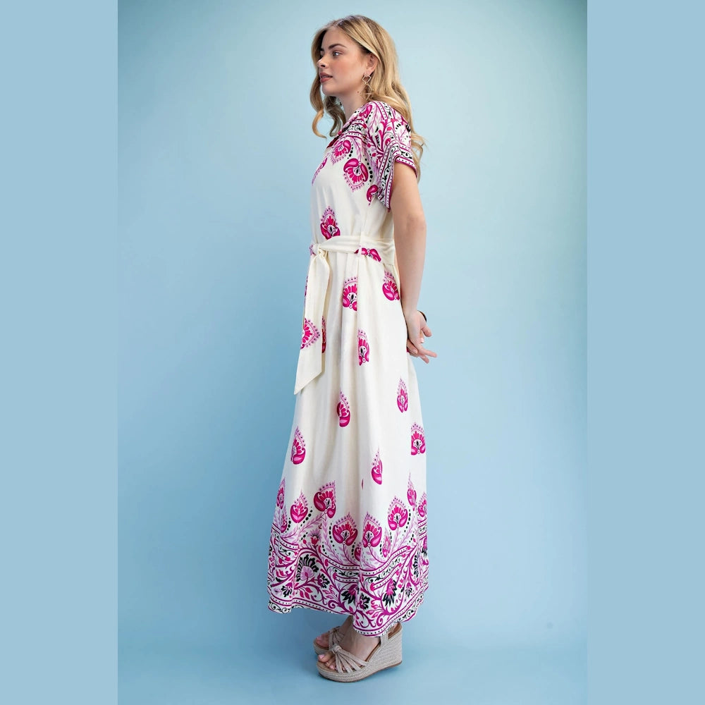 A woman in a white maxi shirt dress with short sleeves and pink patterns, shown in profile on a light blue background.
