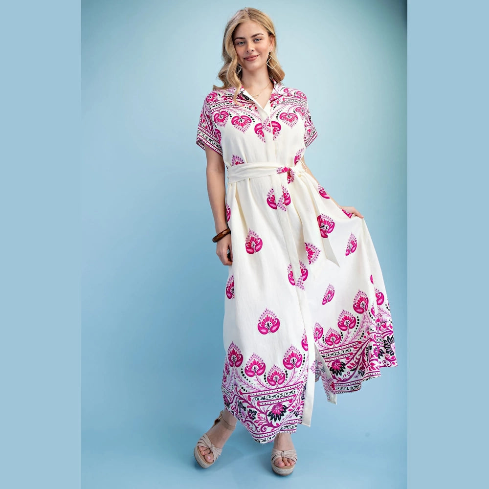 Woman in a berry-mix printed short-sleeve maxi shirt dress with a waist tie and boho pattern on a light blue background.