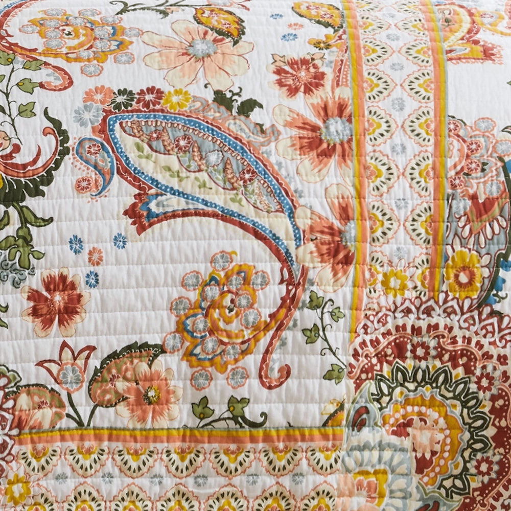 Close-up view of an off-white quilt showing vibrant paisley, floral patterns, and detailed stitching.