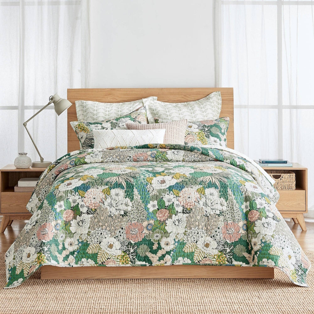 Green and pink floral Bettina quilt set on a wooden platform bed with matching pillows and light wood nightstands.
