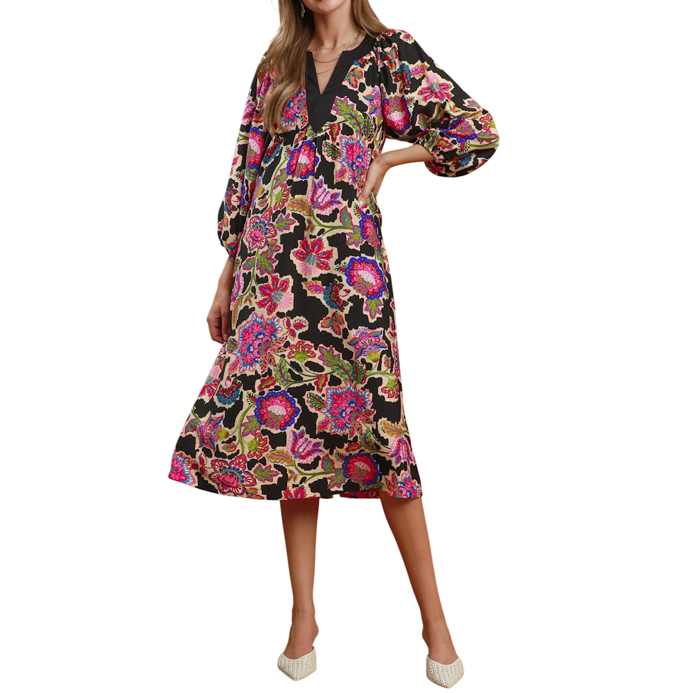 Woman wearing a black midi dress with a vibrant floral print, V-neckline, and long balloon sleeves.