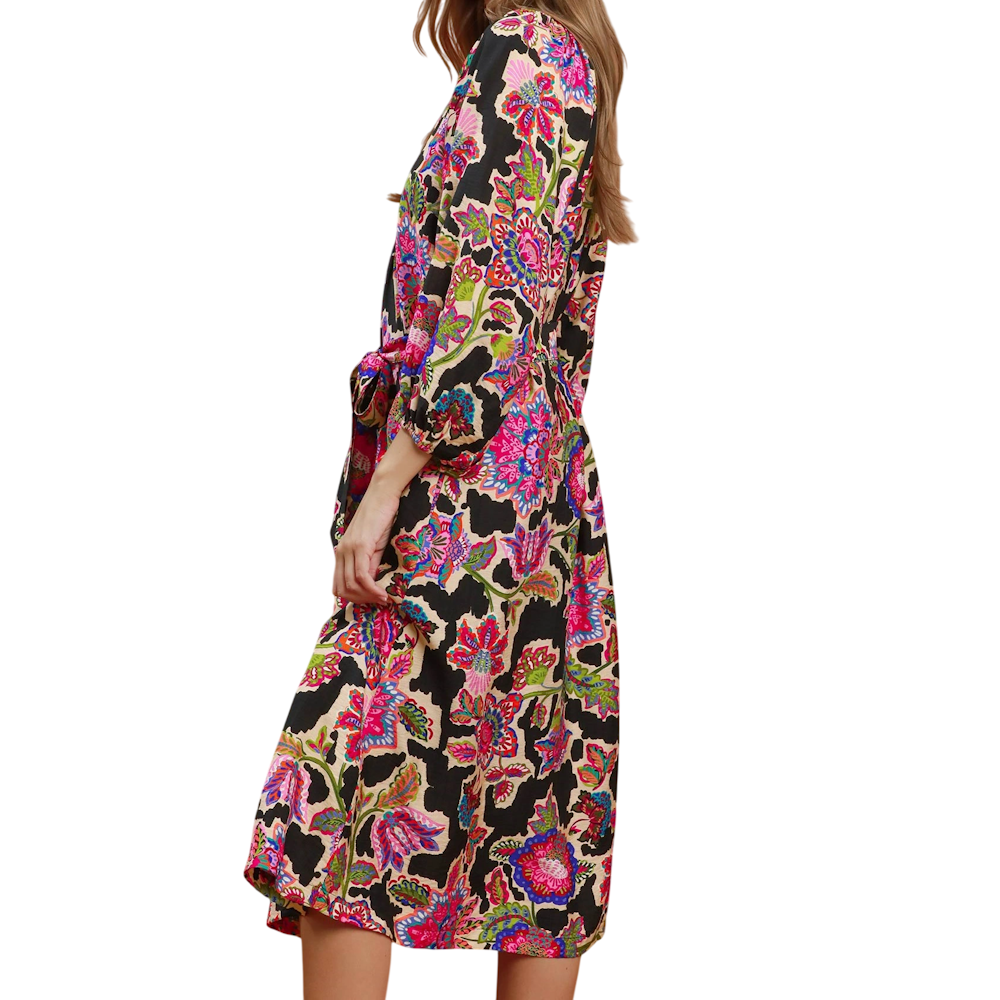 Side view of a midi dress with a colorful floral abstract print on black, 3/4 sleeves, and a tied waist belt.