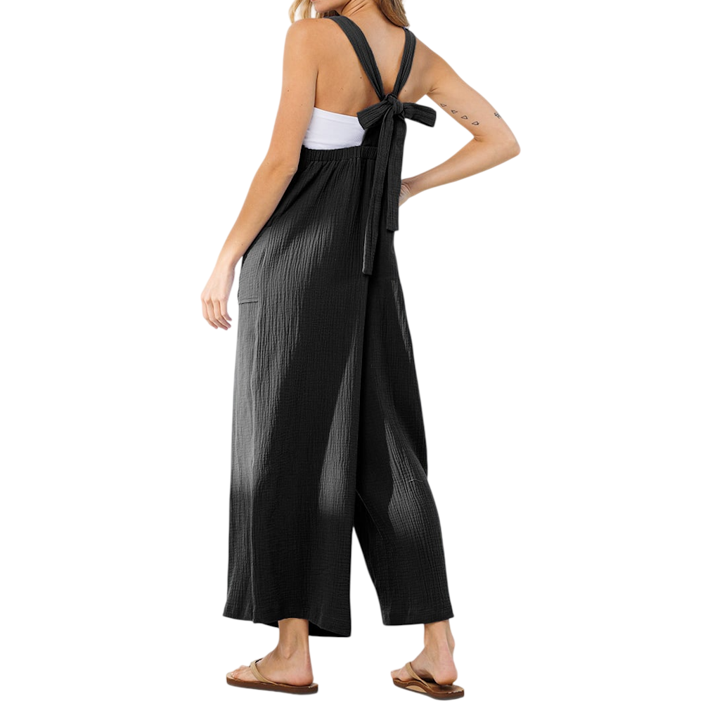 Back view of a woman wearing a black, wide-leg jumpsuit with tie-back straps over a white tube top.
