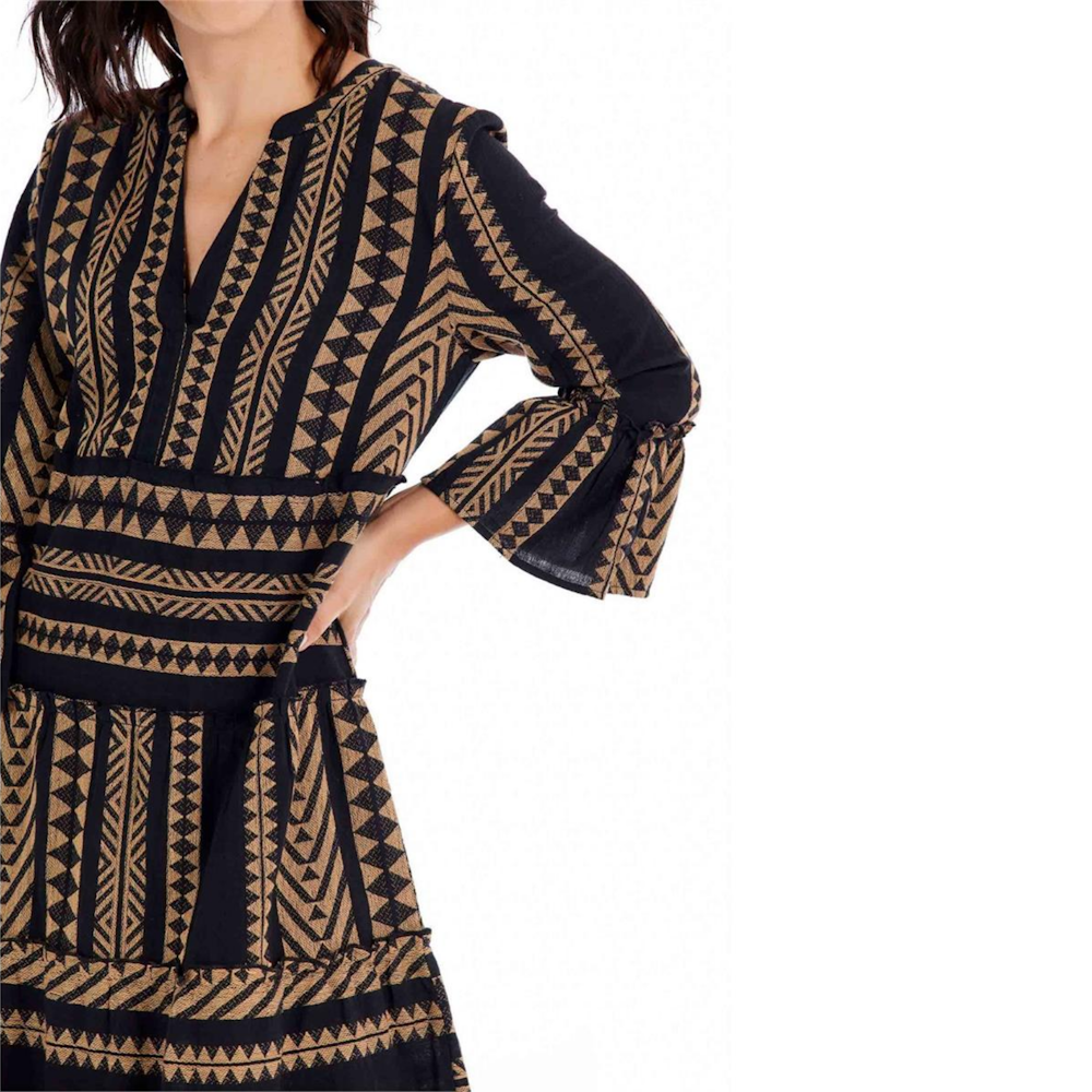 Close-up of a woman wearing a black and brown geometric pattern dress with a V-neck and bell sleeves.