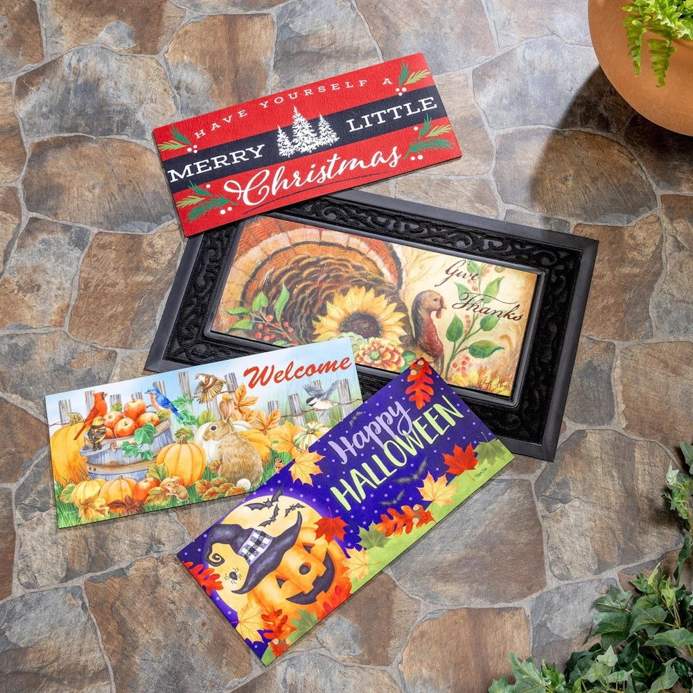 Black rubber mat tray with seasonal holiday inserts for Christmas, Thanksgiving, Halloween, and Autumn on stone floor.