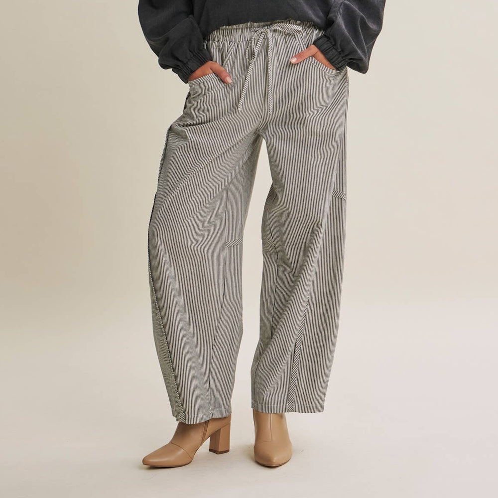 Person wearing black and white striped drawstring barrel pants with beige heeled ankle boots.