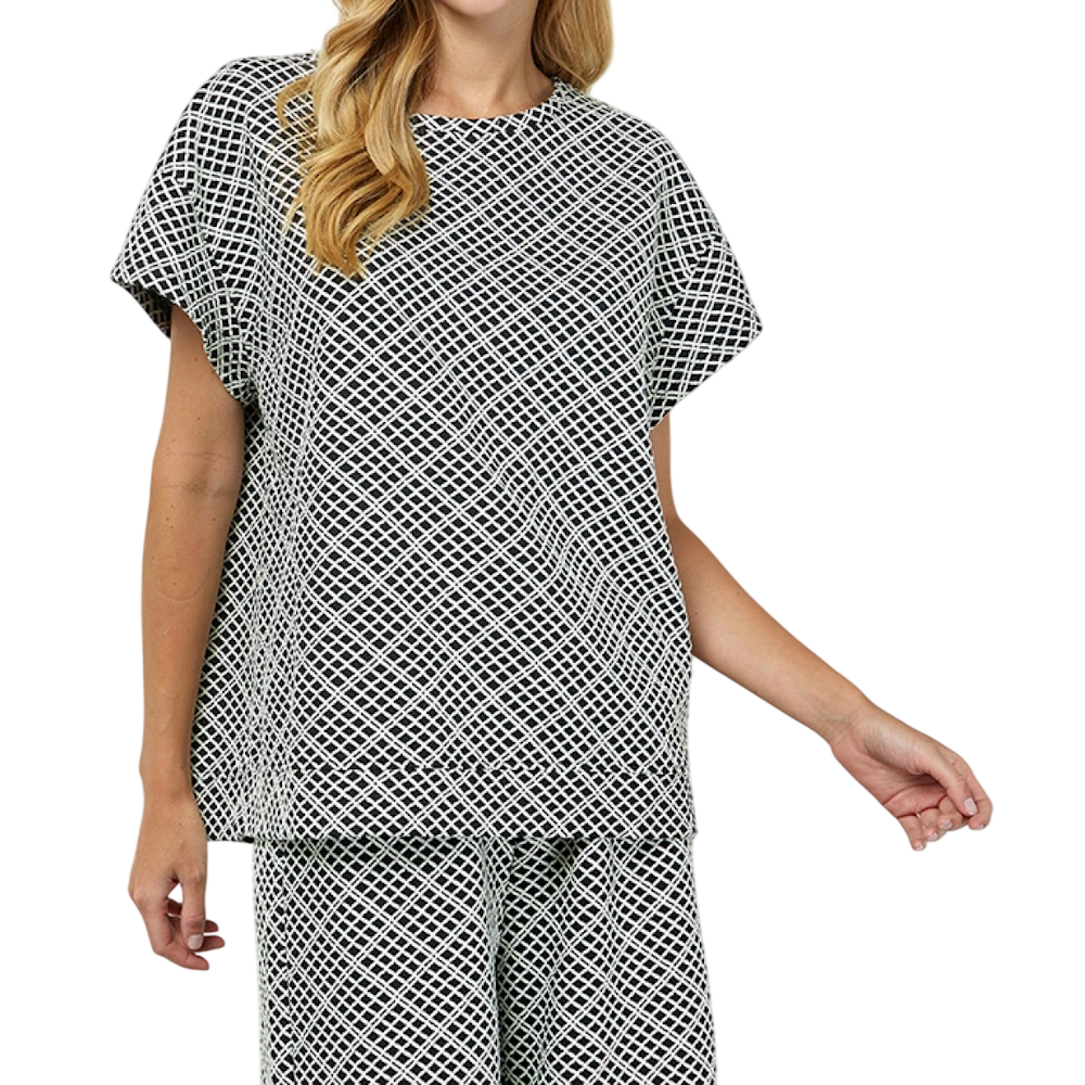 Woman wearing a matching black and white diamond-patterned short-sleeve top and pants set.