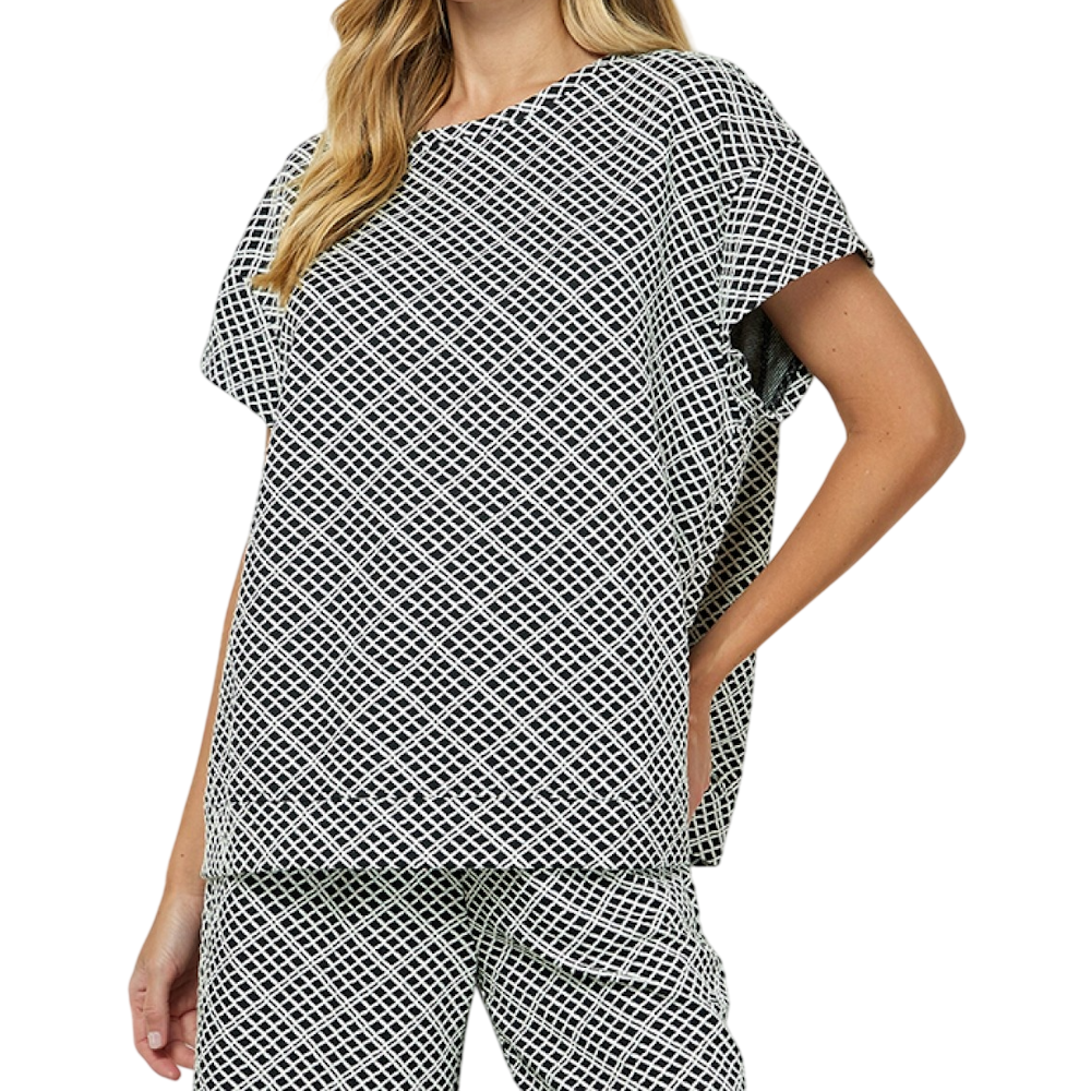Woman in a black and white diamond-patterned, short-sleeve top and matching pants set against a white backdrop.