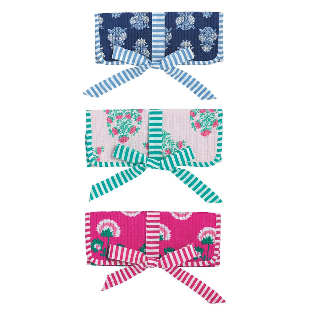 Three block-print quilted jewelry rolls in blue, light pink, and magenta floral patterns with striped ribbon ties.