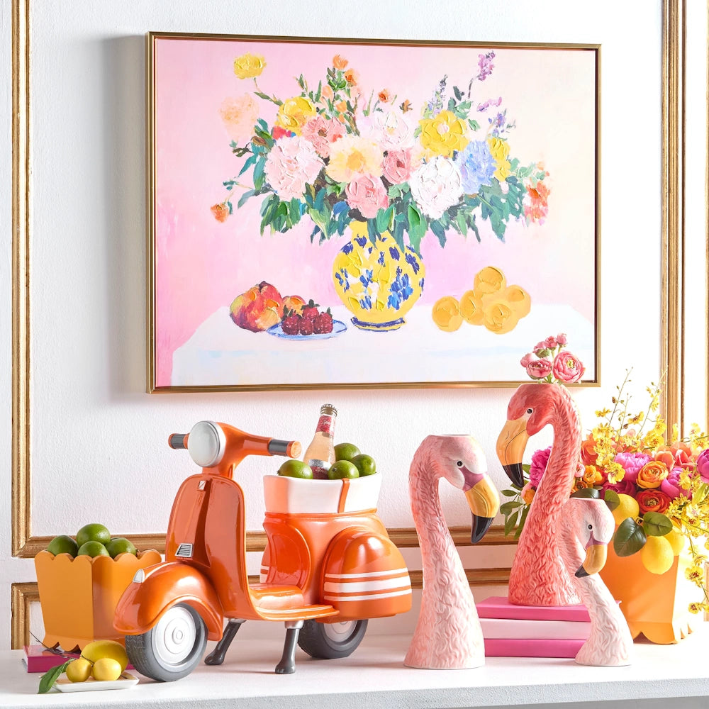 Colorful floral painting above a bright orange scooter and pink flamingo figurines on a white mantel.