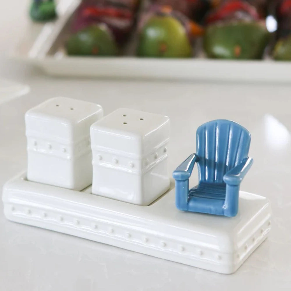 White ceramic salt and pepper shakers next to a small blue Adirondack chair figurine on a matching tray.
