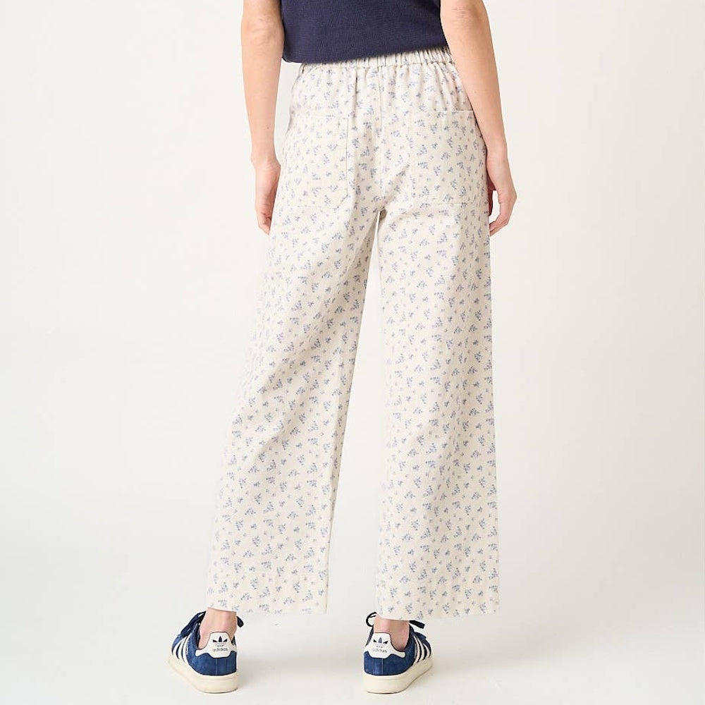 Back view of cream wide-leg pants featuring a blue ditsy floral print and a comfortable elastic waistband.