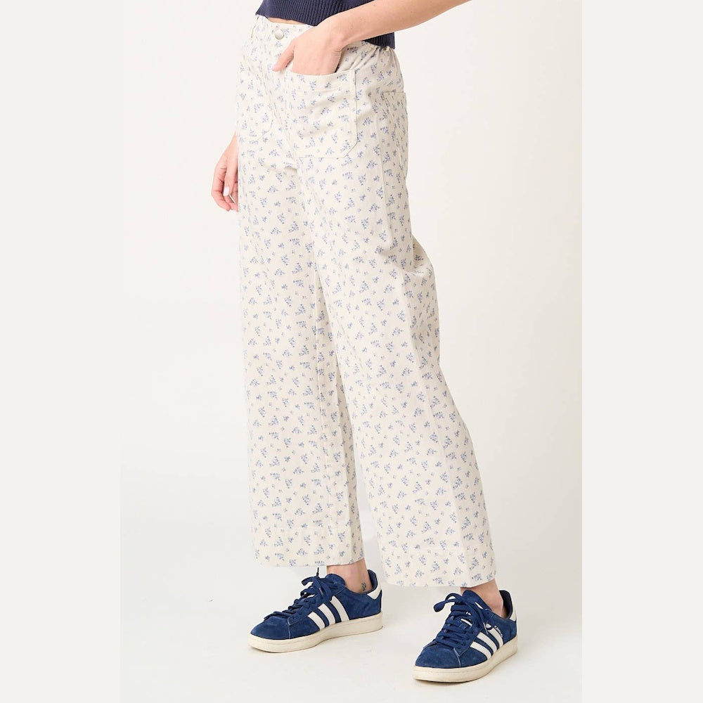 White wide-leg pants with blue ditsy floral print and front pockets, styled with blue and white sneakers.