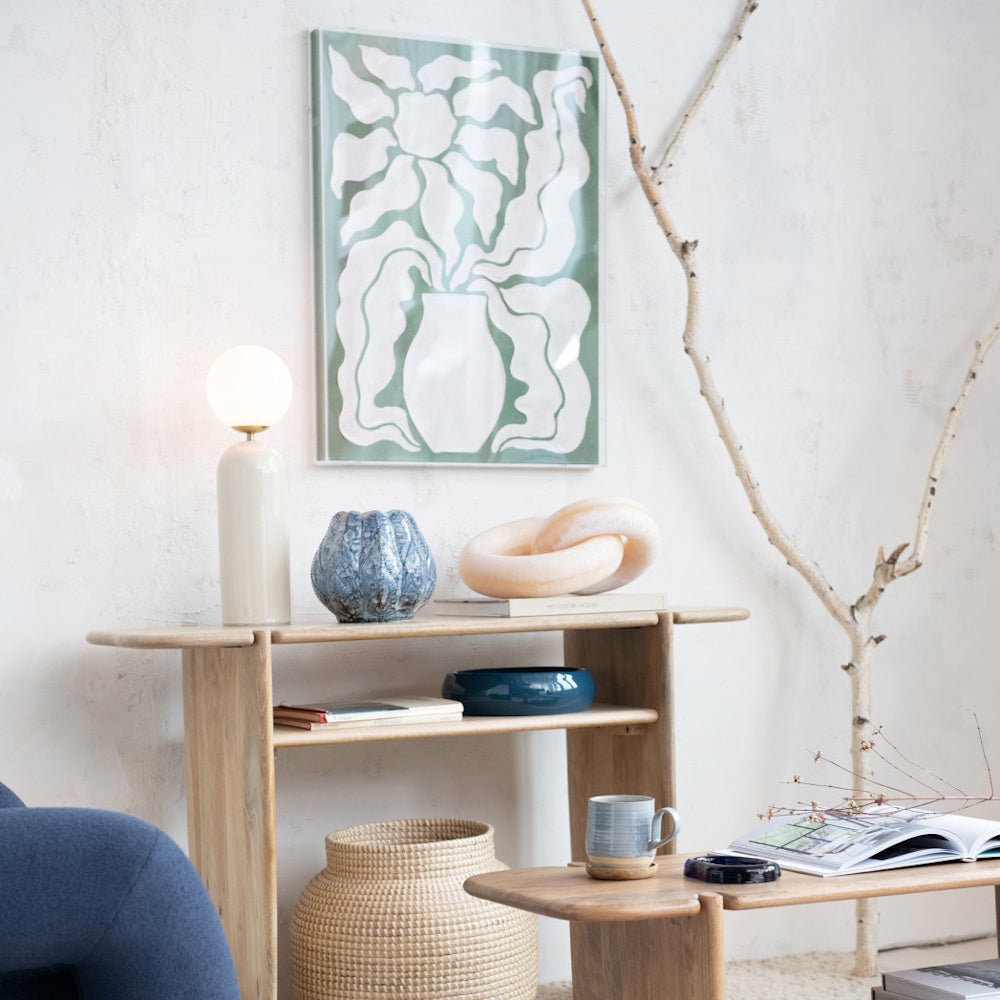 Blue embossed stoneware planter vase on a wooden console table next to a glowing table lamp.