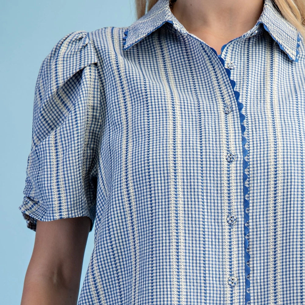 A close-up photograph of a light-blue and white gingham and striped puff-sleeve shirt.