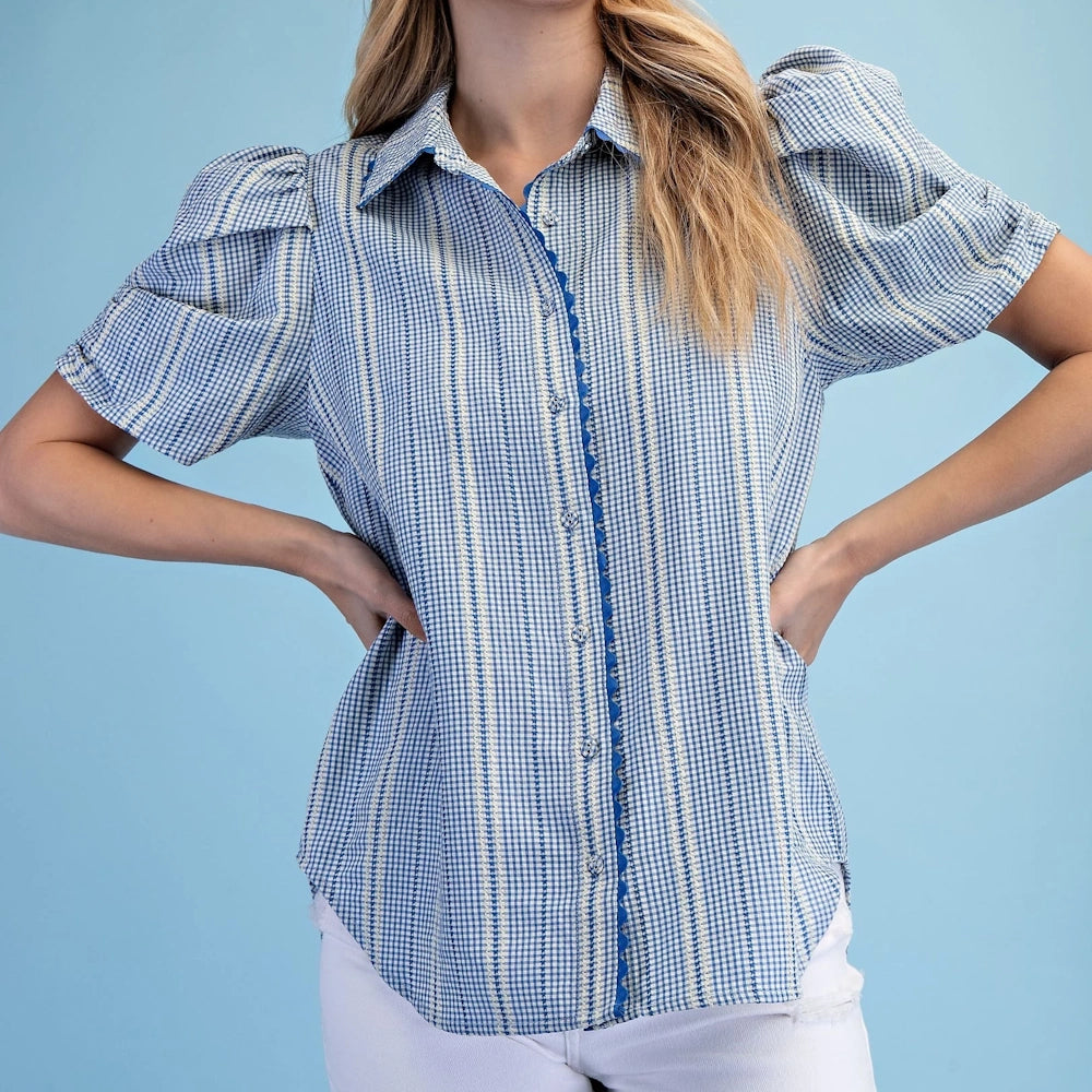 Blue embroidered gingham button-down shirt with ric-rac trim, puff sleeves, and vertical stripes on a woman.