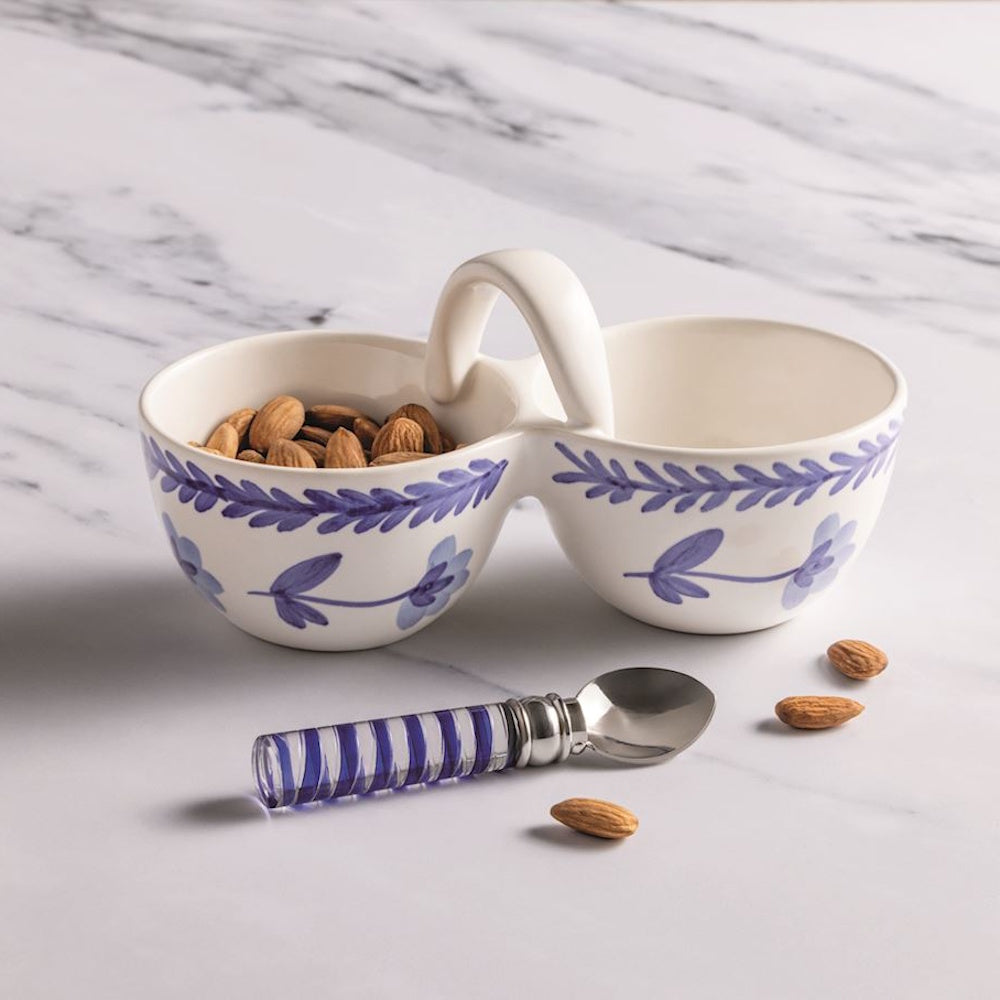 Blue and white floral ceramic double nut bowl with handle, filled with almonds and a matching striped serving spoon.