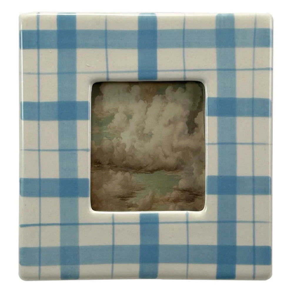 Square blue and white plaid ceramic picture frame featuring a landscape painting of puffy clouds.