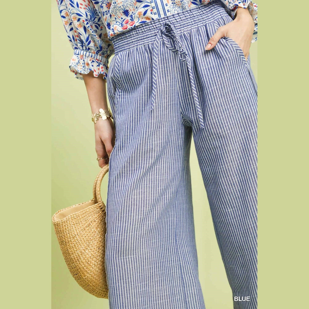 Blue and white vertical striped wide-leg linen pants with a drawstring elastic waistband and side pockets.