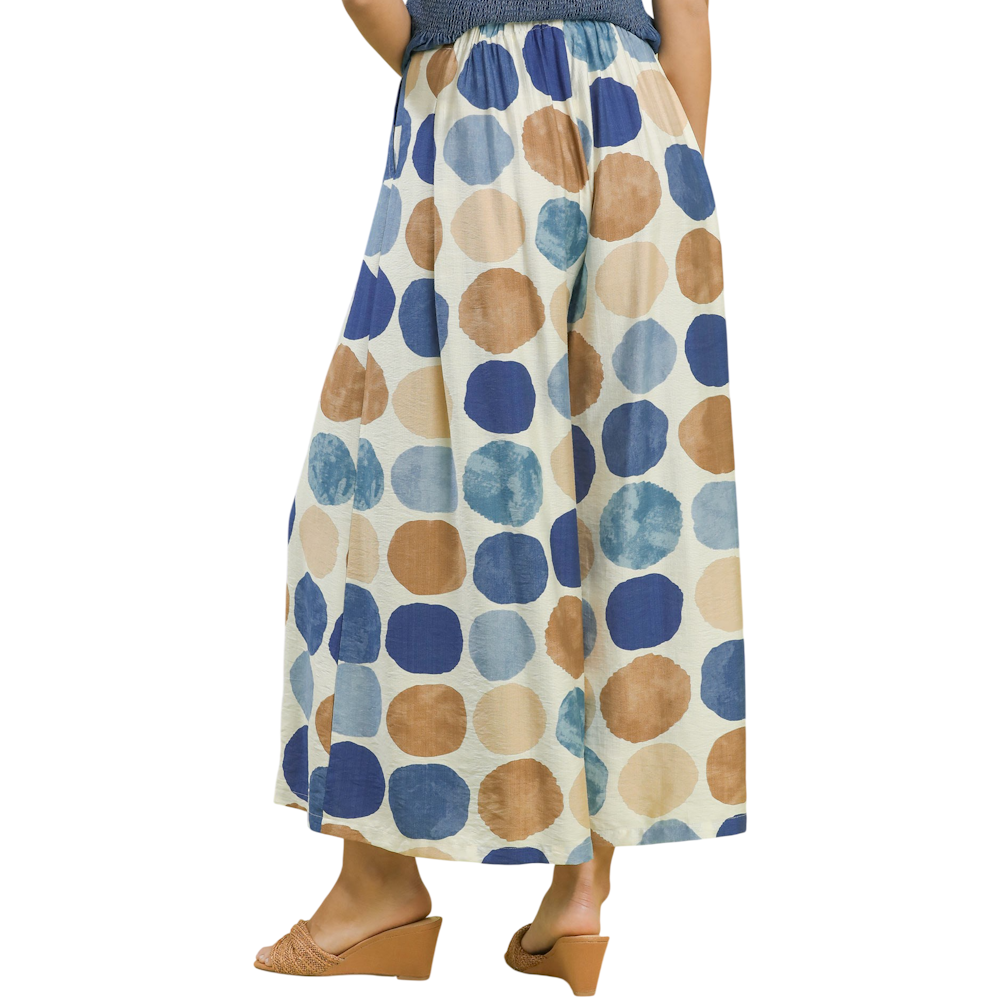 High-waisted wide-leg pants featuring large blue and brown polka dots on a cream background.
