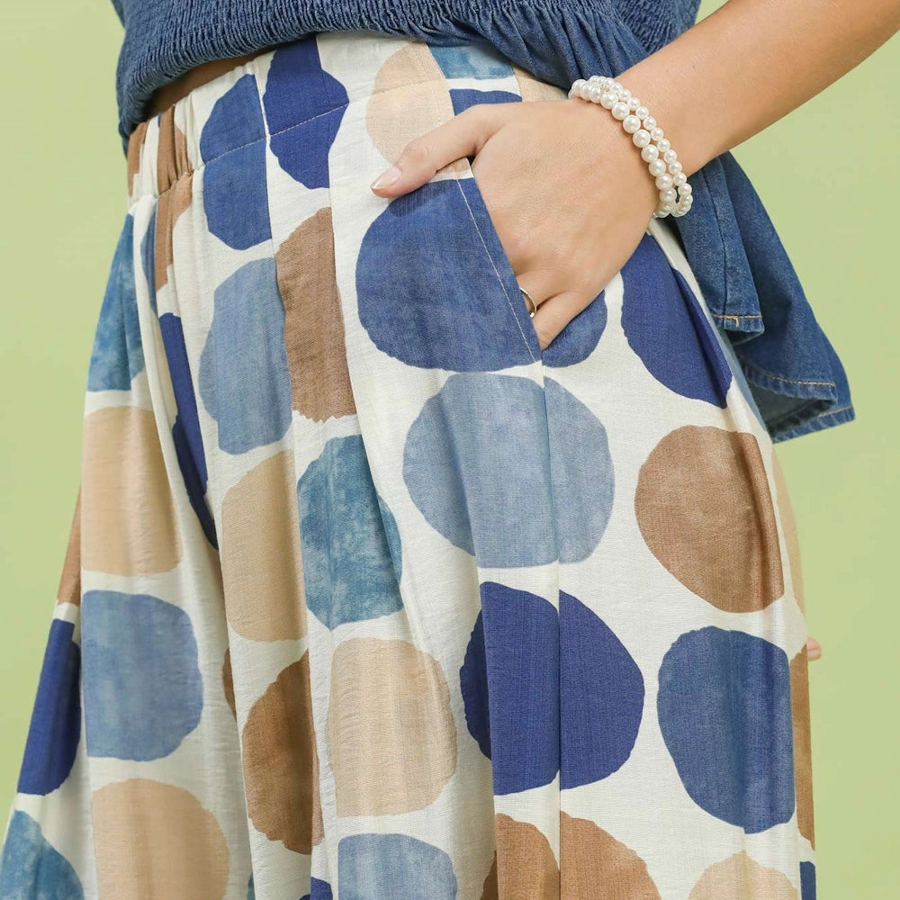 Close-up of high-waisted pants with large blue, light blue, and beige polka dots and a side pocket.