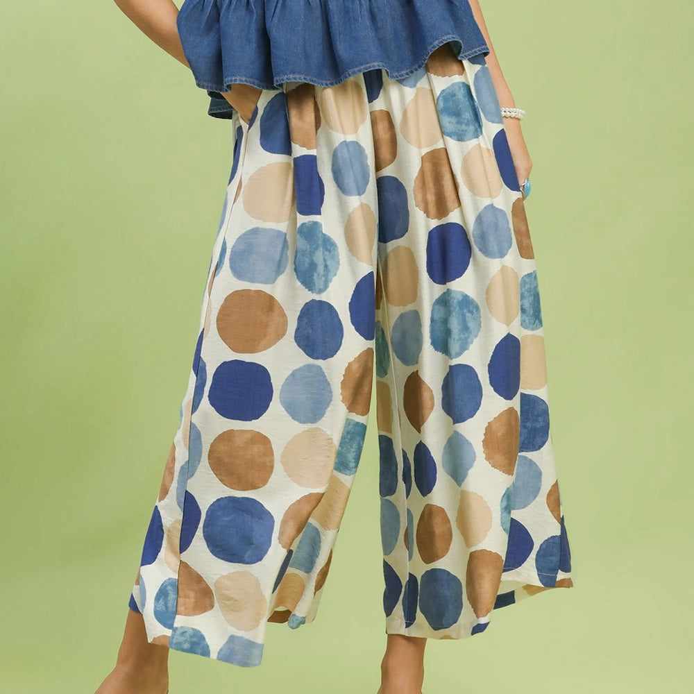 Wide-leg, high-waisted pants with large blue and tan polka dots on a cream background.