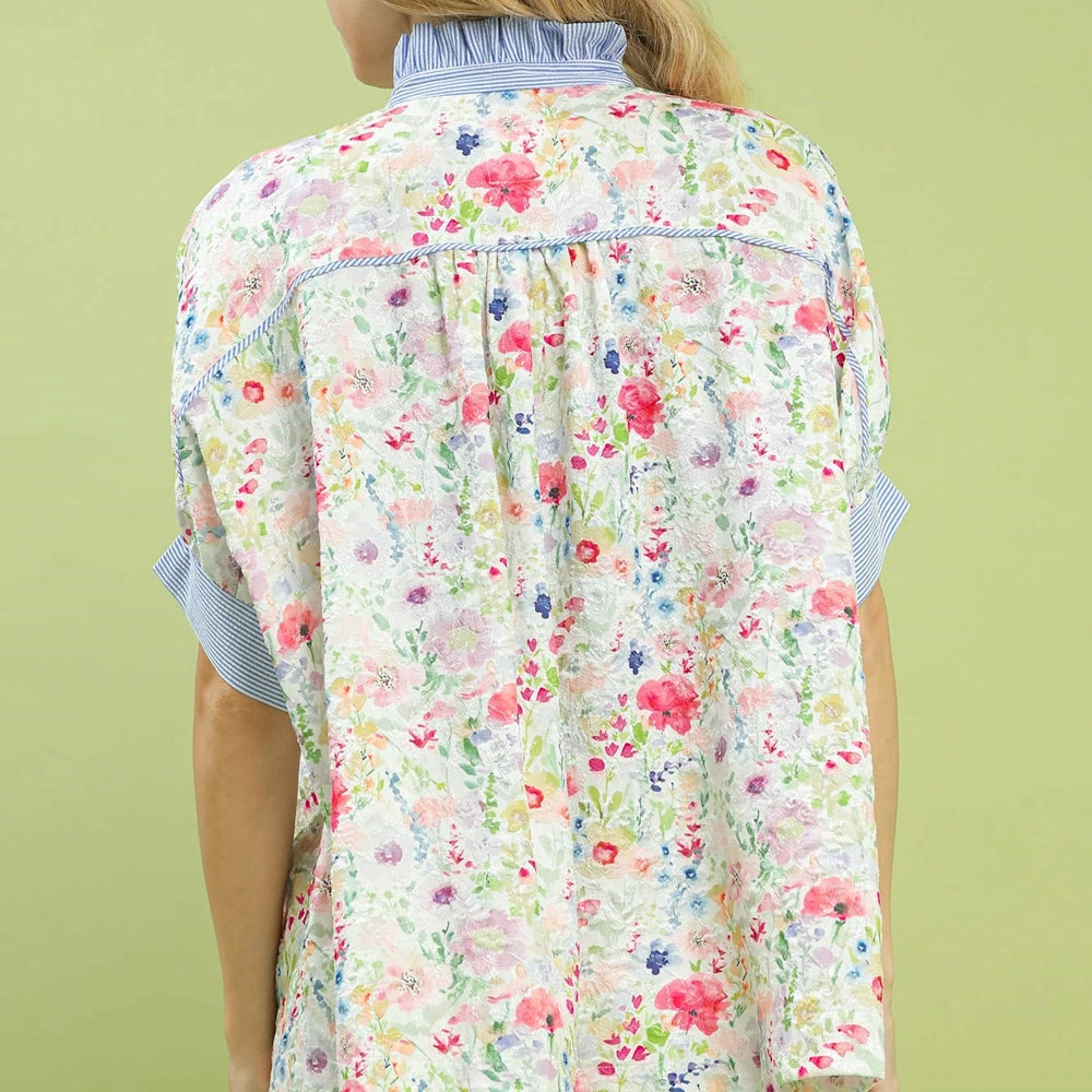 Back view of a floral jacquard button-down top featuring pink and blue flowers with blue striped collar and sleeve cuffs.