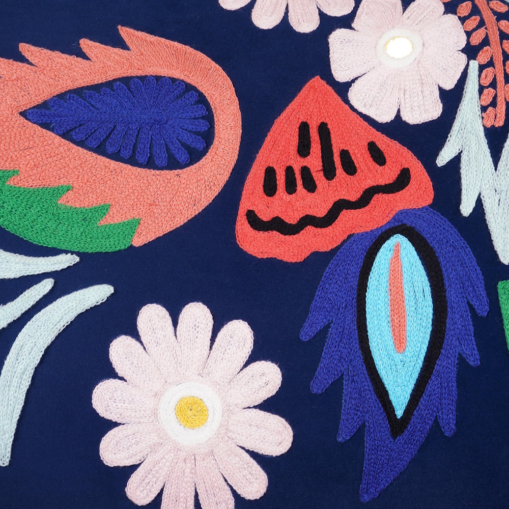 Close up of colorful floral embroidery on navy blue upholstery, showcasing intricate stitched detailing.