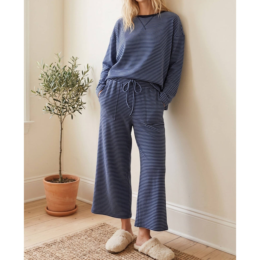 Woman wearing a blue and navy thin-striped lounge set featuring a long-sleeve top and wide-leg drawstring pants.